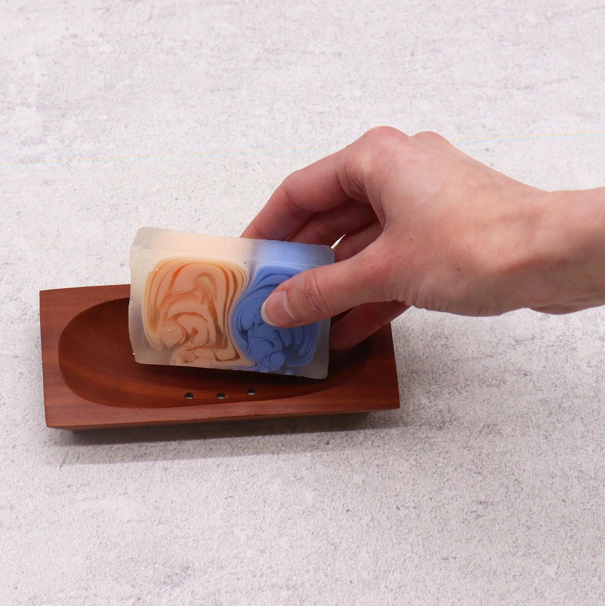 Jabonera rectangular de madera de caoba color marrón rojizo con ranuras de drenaje, sosteniendo una pastilla de jabón.