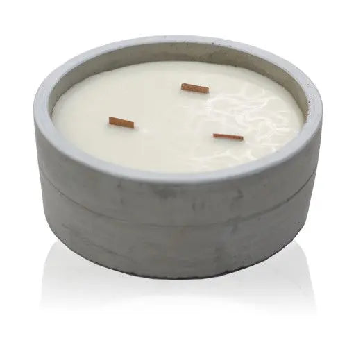 Vela redonda de cera blanca con tres mechas de madera en un recipiente de hormigón gris de estilo minimalista industrial