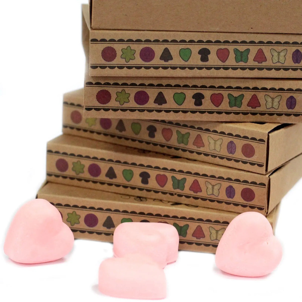 Cajas de cartón kraft apiladas con figuras de cera de soja rosa en forma de corazón en primer plano.