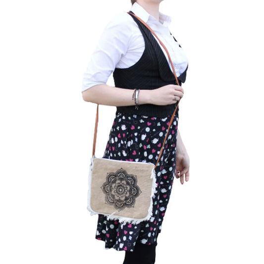Bolso bandolera de tela tipo arpillera con estampado de mandala negro y flecos decorativos en los bordes