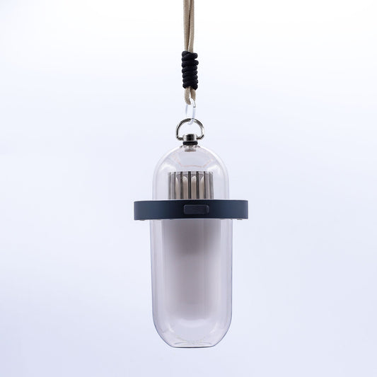 Lámpara portátil blanca de diseño cilíndrico con efecto llama, aro gris, puerto USB y cuerda de sujeción, fondo blanco.