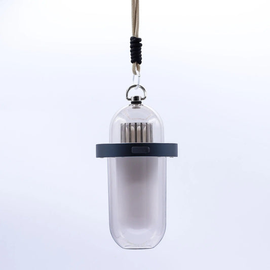 Lámpara portátil blanca de diseño cilíndrico con efecto llama, aro gris, puerto USB y cuerda de sujeción, fondo blanco.