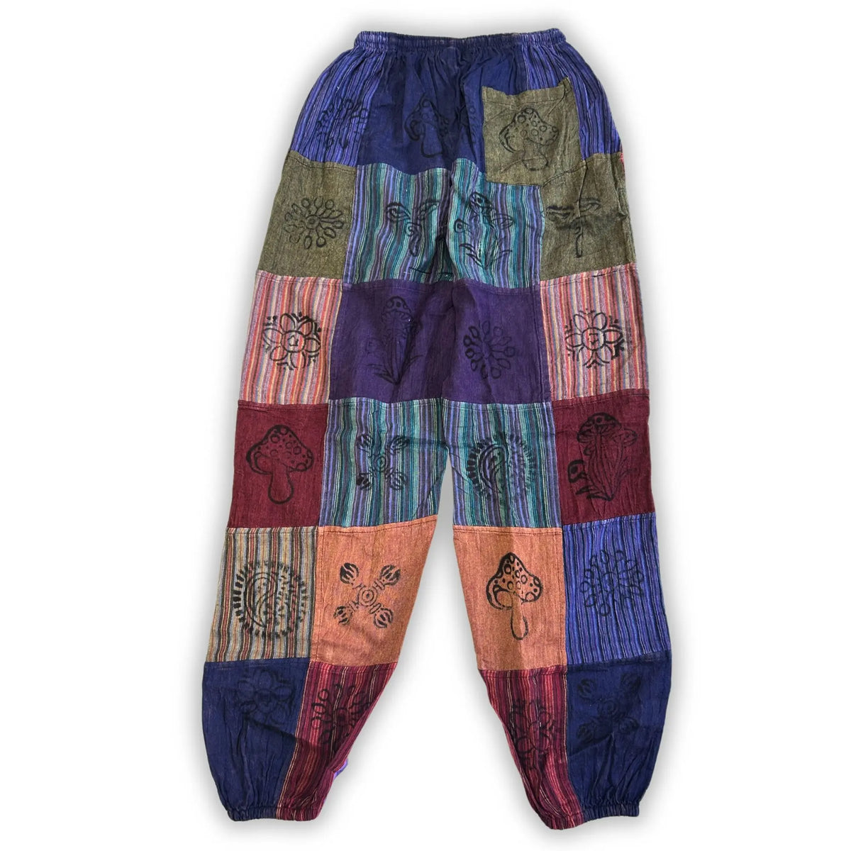 Pantalones de patchwork en tonos morados, verdes y anaranjados, con bordados artísticos de flores y setas.