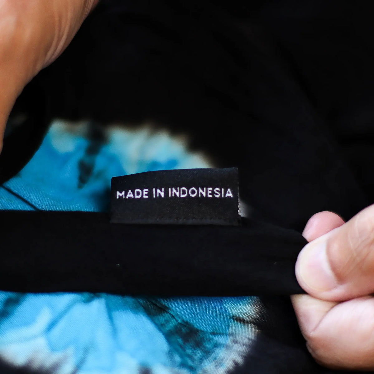 Etiqueta de tela en pantalones Ancient Wisdom negros y azules con estampado estilo japonés; se lee "MADE IN INDONESIA".