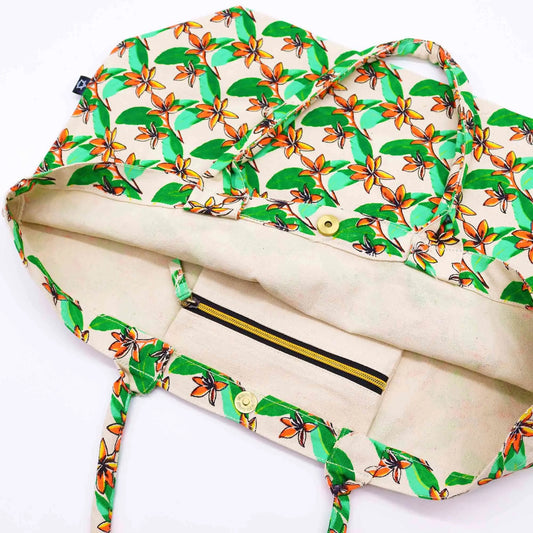Bolsa de tela color crema con estampado de flores de frangipani naranjas y hojas verdes, cierre de broche y cremallera.