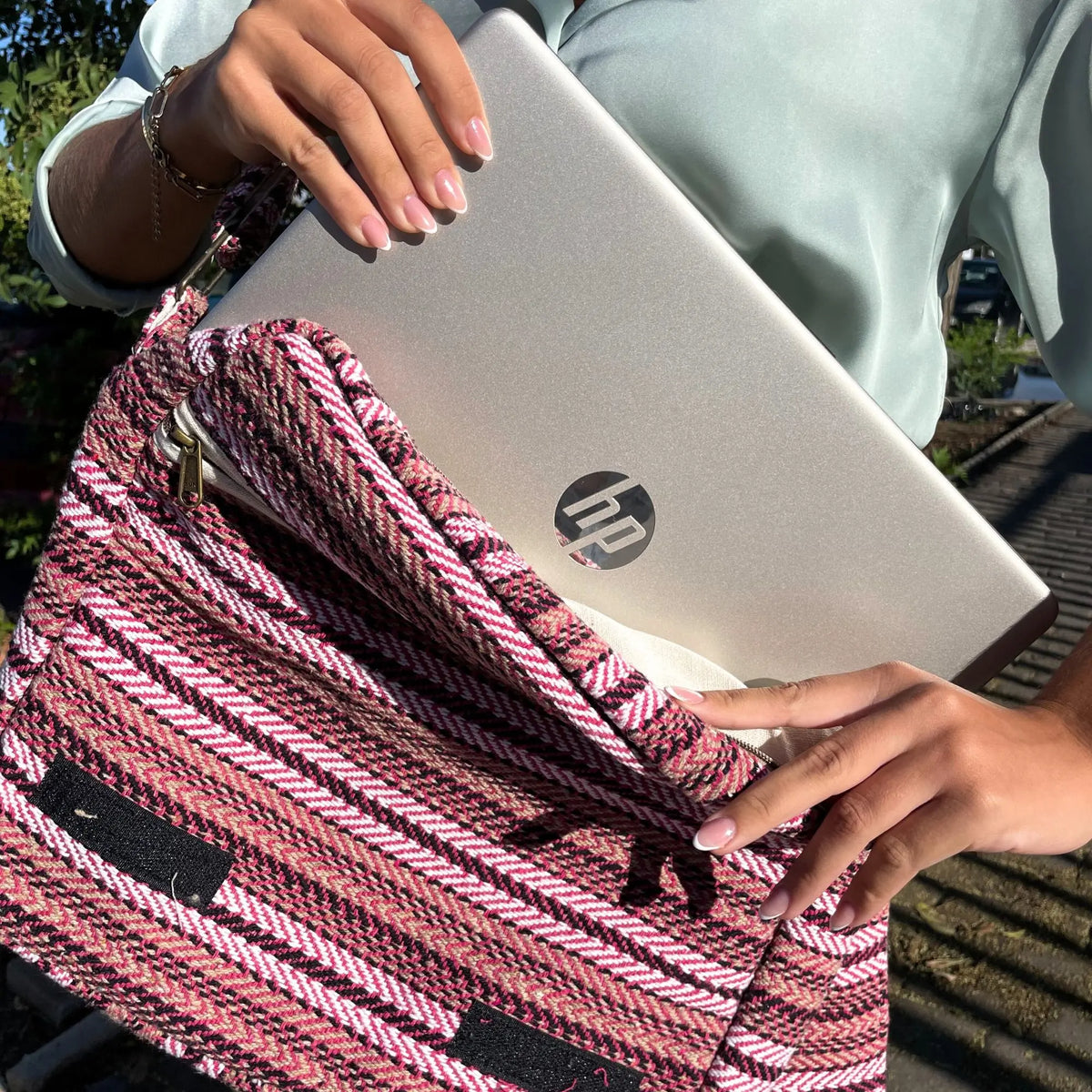 Bolso para portátil de tela tejida con patrón de rayas rosa, blanco y negro. Estilo artesanal con cierre de cremallera.