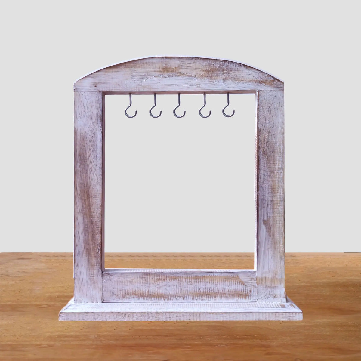 Soporte de madera blanqueada hecho a mano, rectangular con arco superior y cinco ganchos metálicos para colgar.