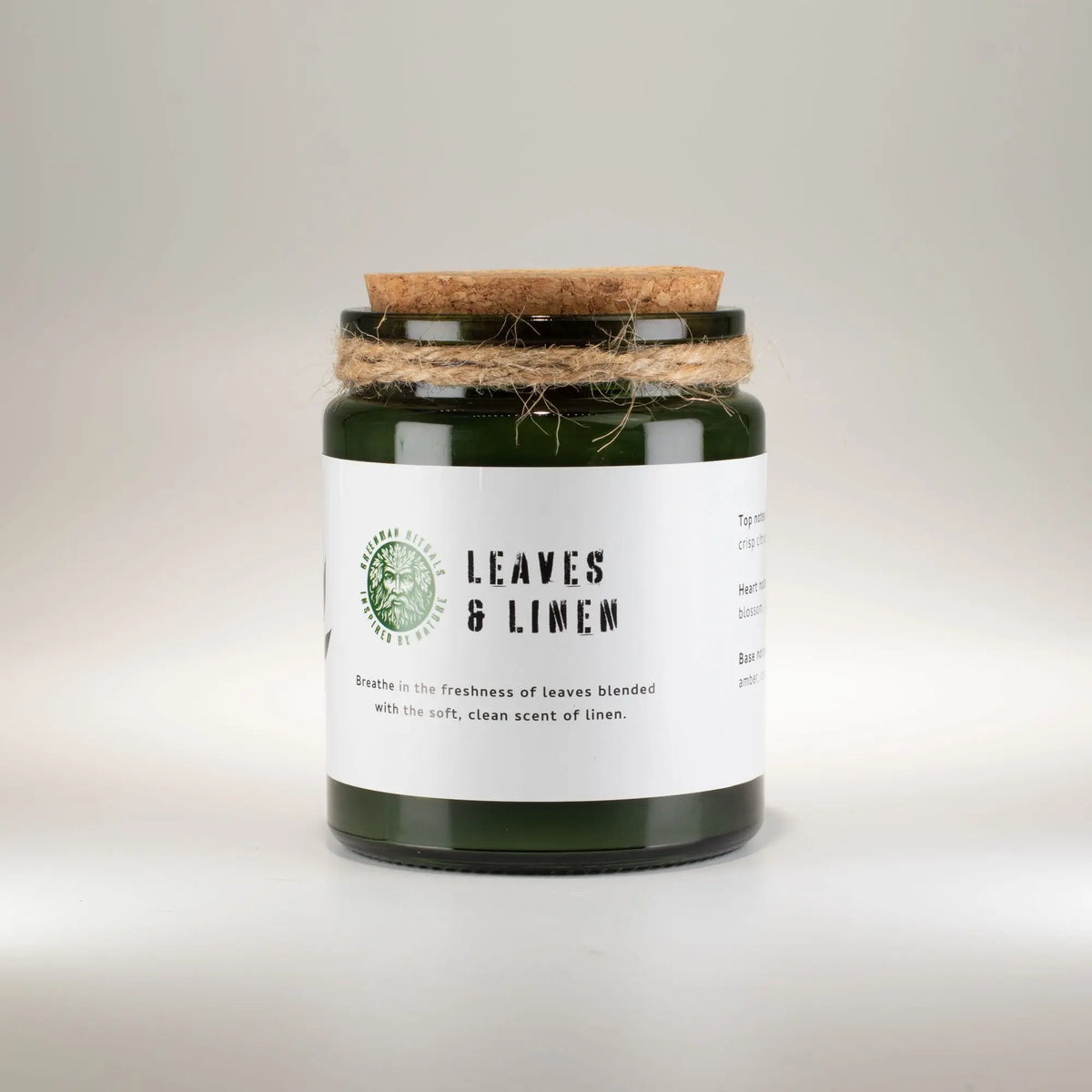 Vela aromática verde en frasco de vidrio con tapa de madera, fragancia a hojas y lino.