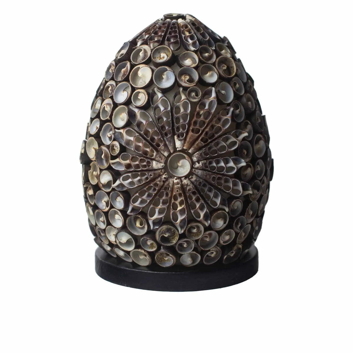 Lámpara ovalada estilo boho hecha de conchas marinas color chocolate con patrón floral, sobre base circular negra.