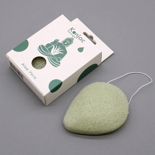 Esponja facial Konjac verde en forma de gota con cuerda, junto a su caja de cartón blanca ilustrada.