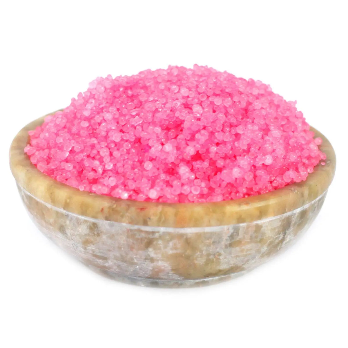 Cuenco de piedra natural conteniendo gránulos aromáticos de color rosa intenso sobre fondo blanco.