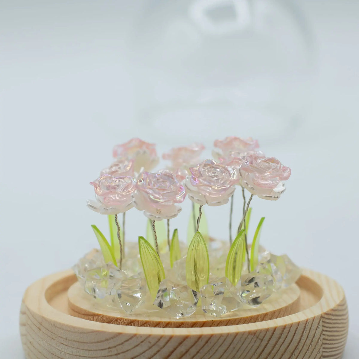 Domo Floral Glow: 10 rosas rosadas brillantes sobre base de madera con cristales y luz LED, estilo decorativo elegante.