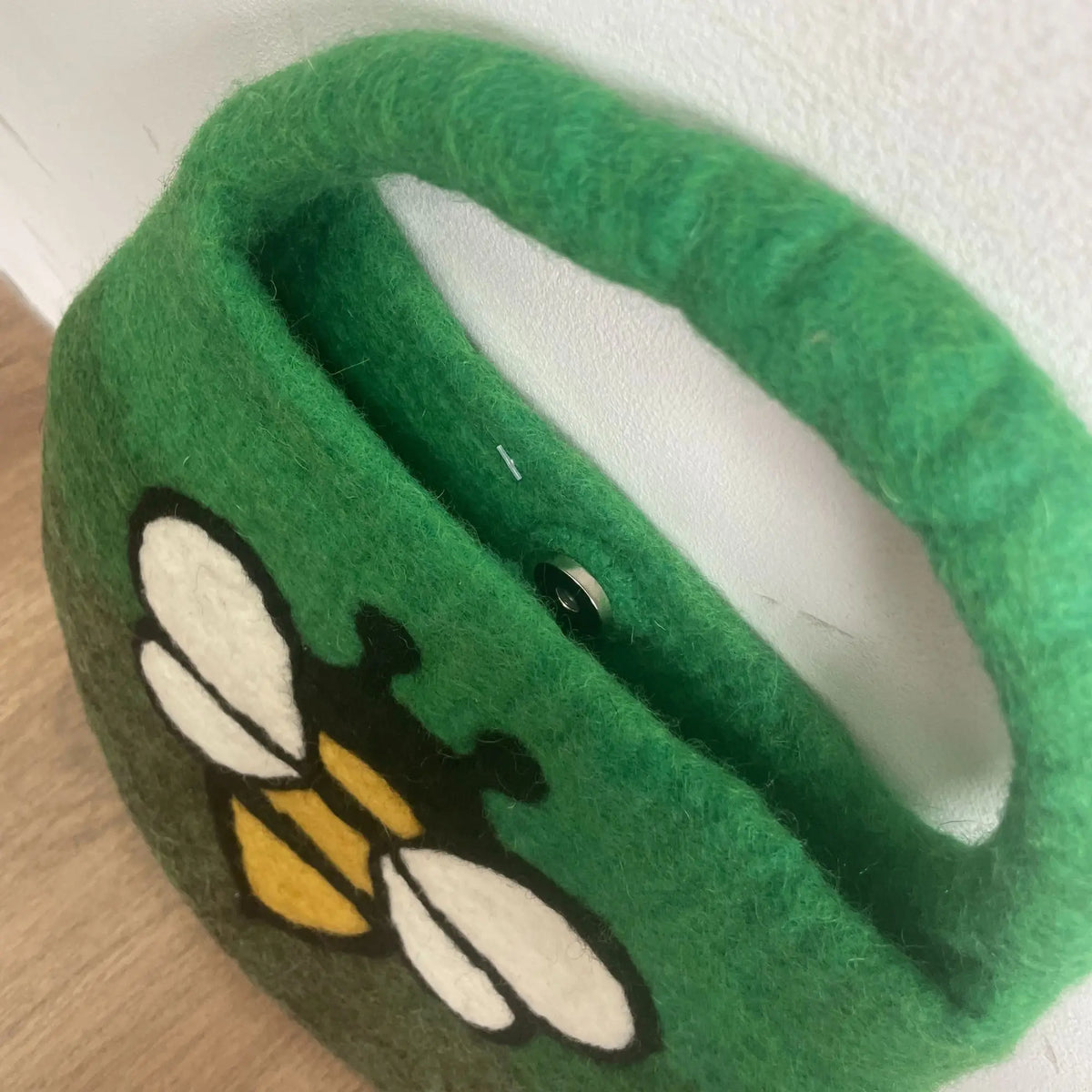 Bolso de fieltro verde con diseño de abeja, cierre de imán y asa integrada, estilo artesanal.