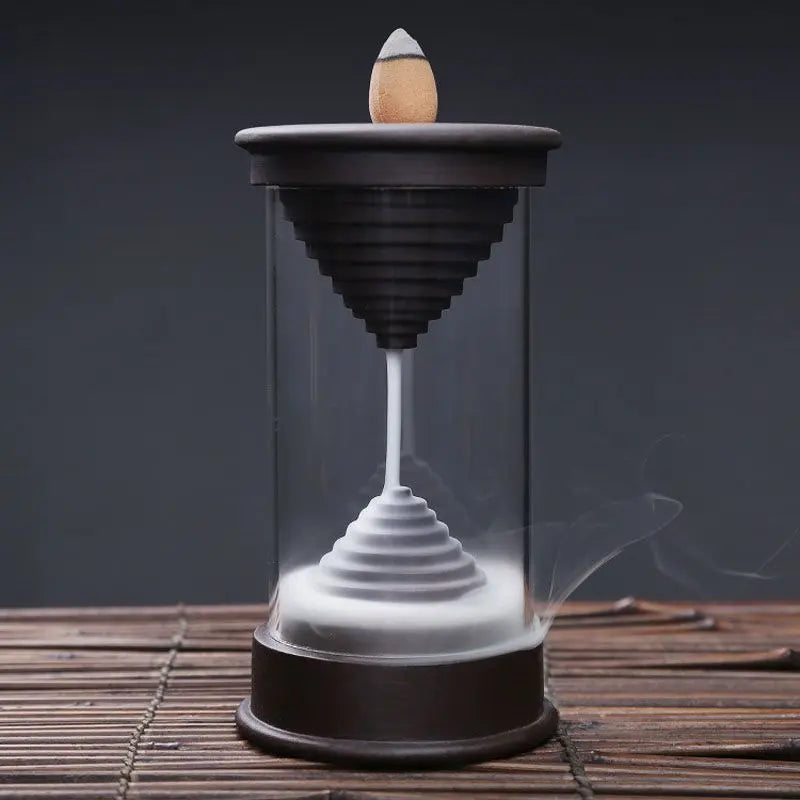 Quemador de incienso de flujo inverso, con diseño tubular de vidrio, base de madera y humo descendente en espiral.