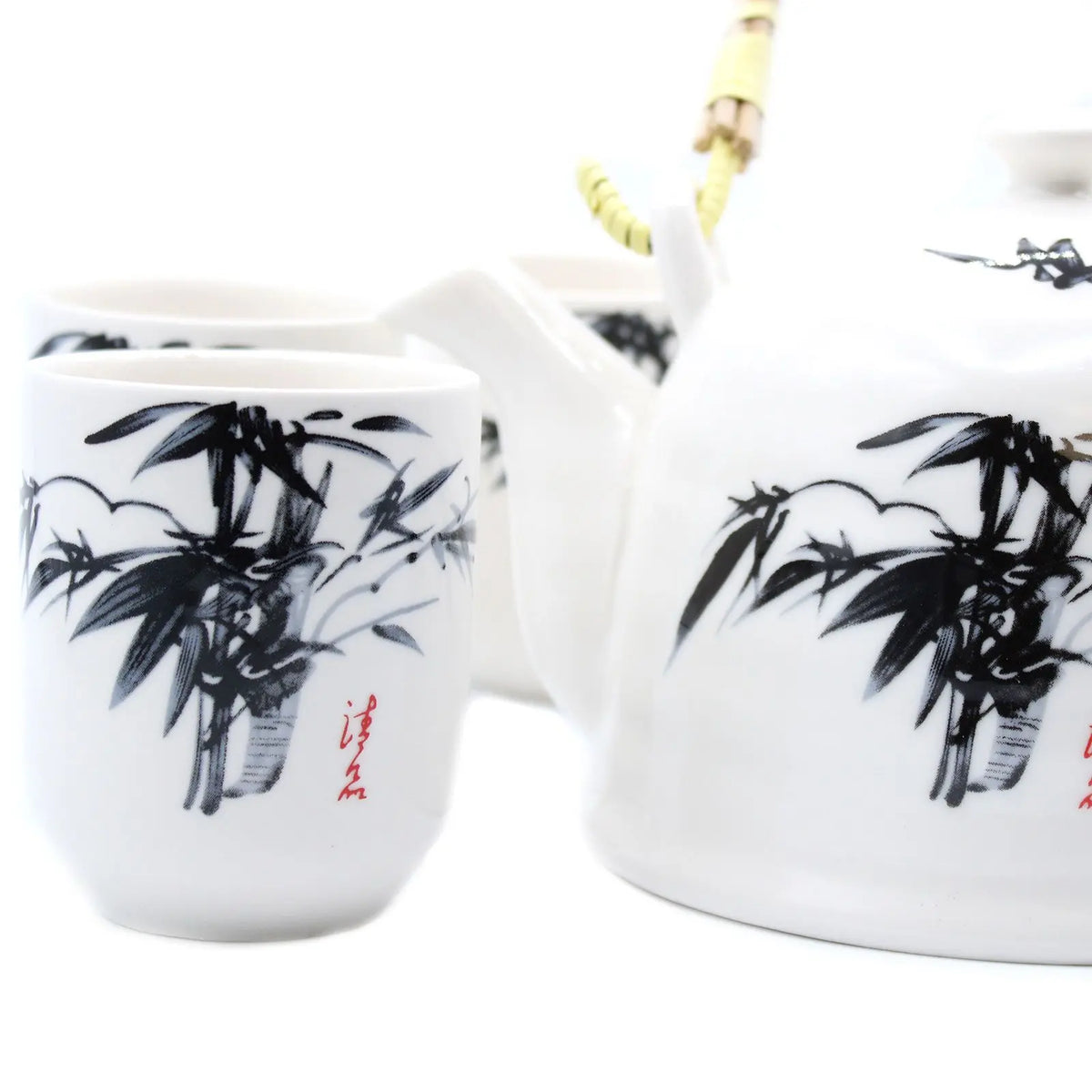 Set de té oriental de cerámica blanca con estampado de bambú negro y asa de fibra. Incluye tetera y tazas elegantes.