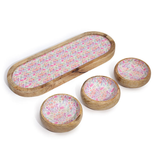 Bandeja alargada y tres cuencos redondos de madera de mango con interior decorado con estampado floral en tonos pastel.