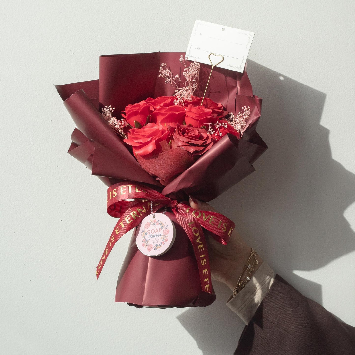 Ramo de flores rojas envuelto en papel marrón con cinta dorada, estilo elegante. Perfecto para ocasiones especiales.