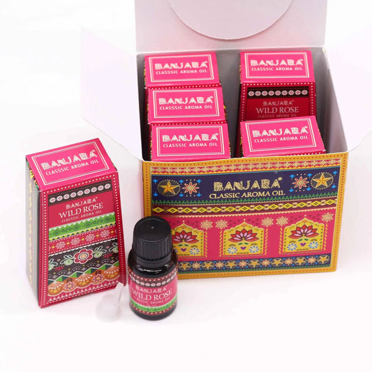 Caja abierta con frascos de aceite de rosa silvestre y envases de cartón decorados con motivos étnicos coloridos.
