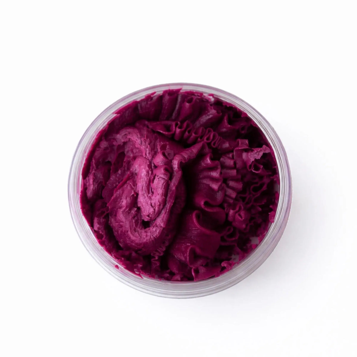 Crema de color púrpura en tarro transparente, con textura suave y rizada, ideal para tratamientos de belleza.