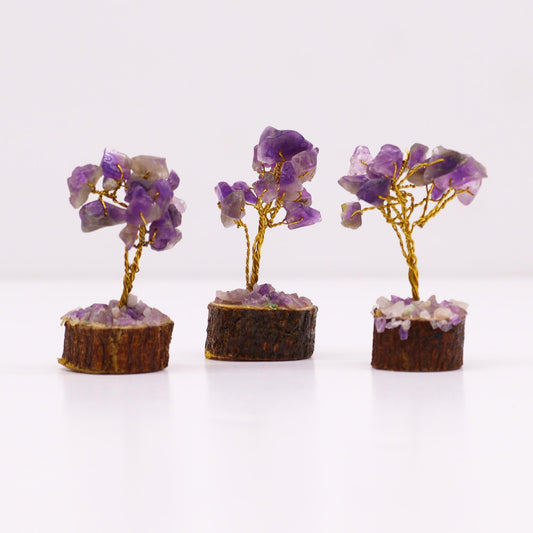 Tres mini árboles decorativos con hojas de amatista, ramas de alambre dorado y base de tronco de madera natural.