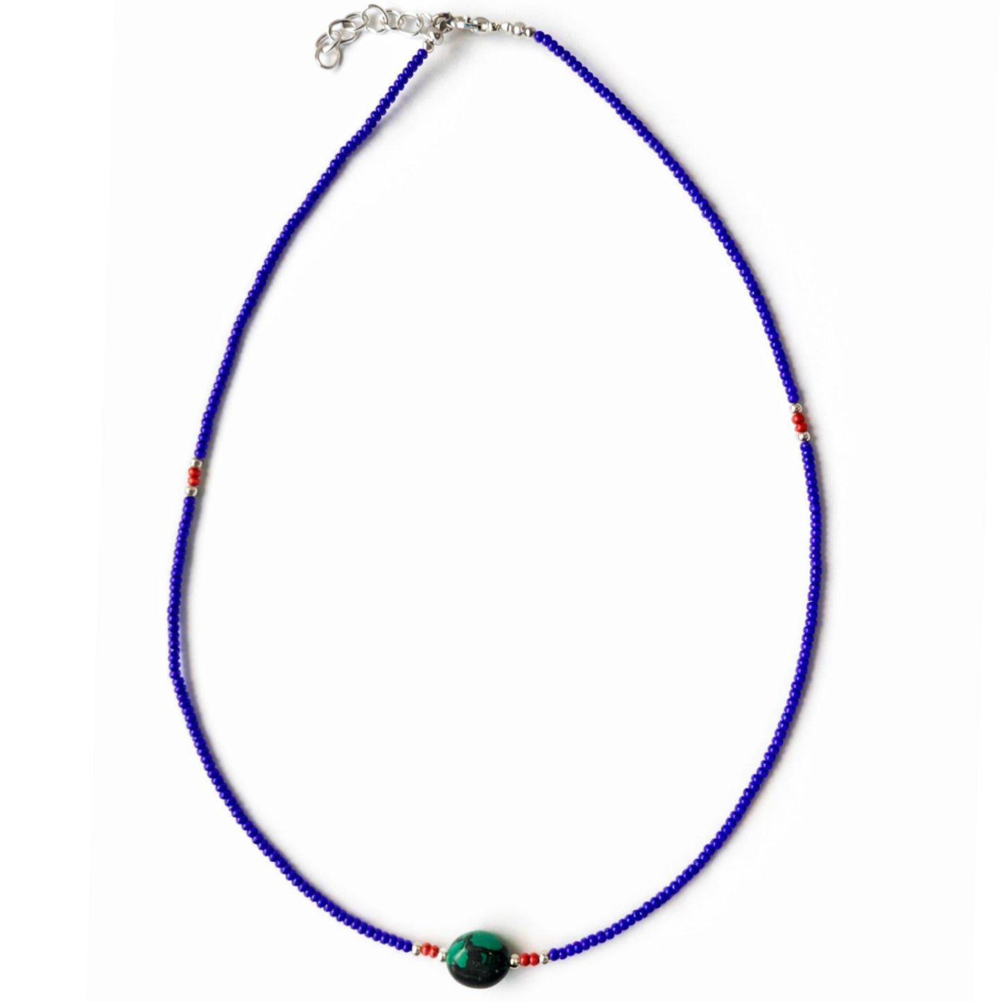 Collar de cuentas azules, con detalles en rojo y una piedra verde, estilo bohemio.