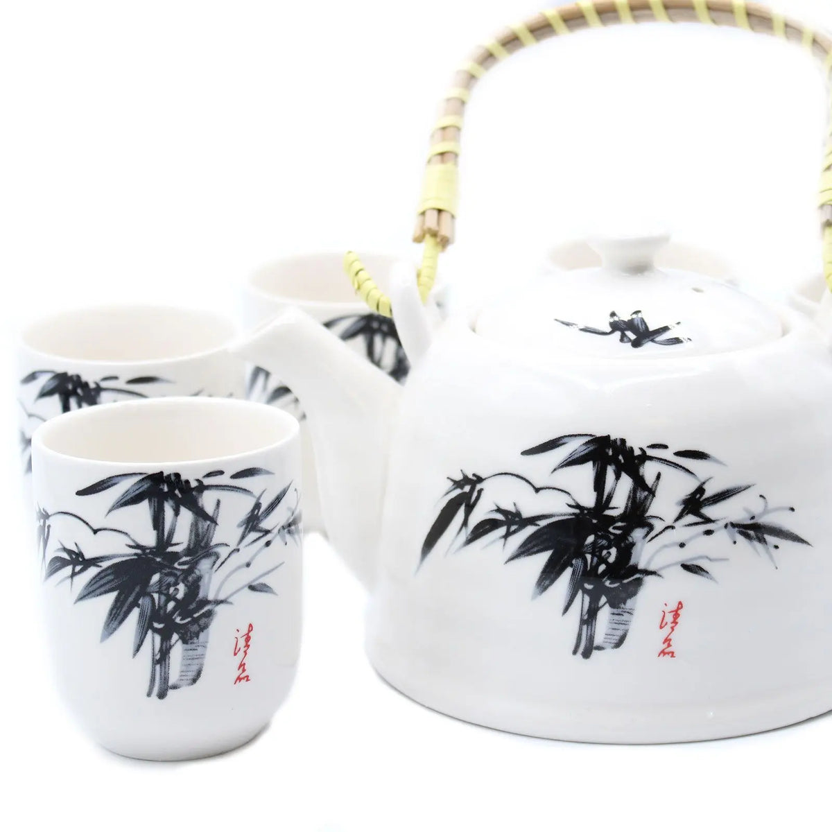 Set de tetera Ancient Wisdom en cerámica blanca con diseño de bambú negro y asa de mimbre, incluye varias tazas.