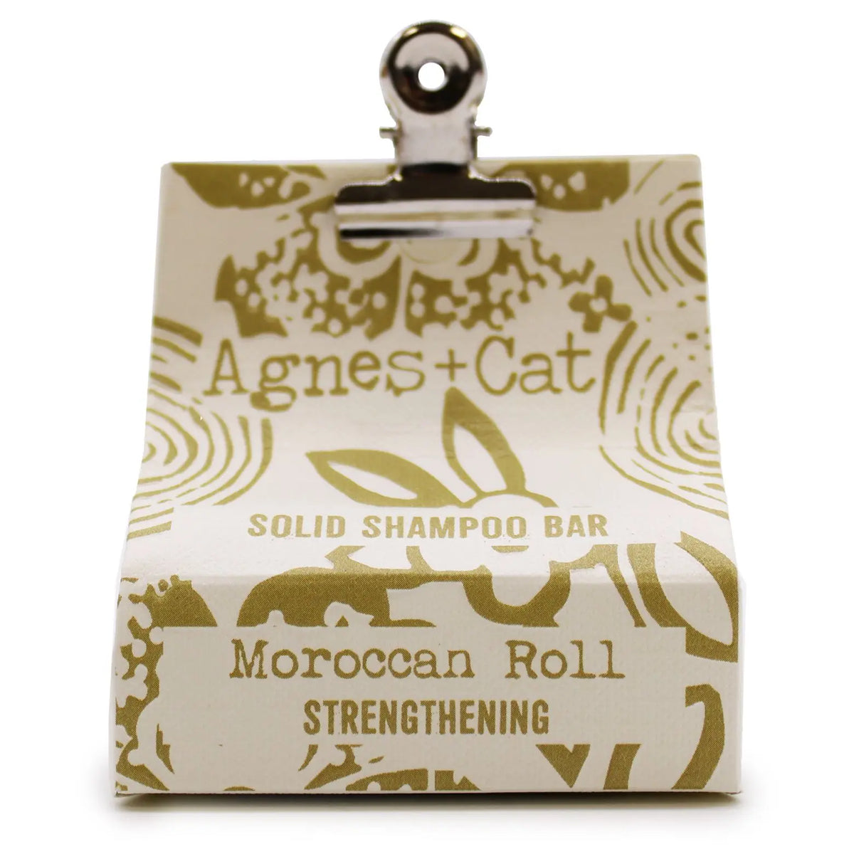 Champú sólido Agnes + Cat, envase papel crema con diseño dorado y clip metálico, aroma "Moroccan Roll" fortalecedor.