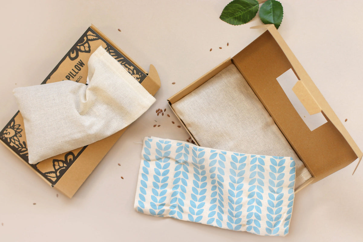 Almohadillas relajantes de tela en cajas de cartón. Diseño natural con estampado de hojas azules y tonos beige.
