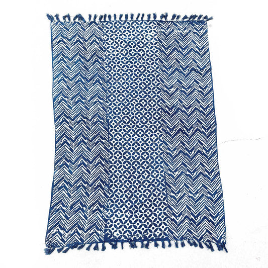 Manta azul y blanca de algodón con diseño geométrico y flecos en los bordes, estilo bohemio ideal para decoración.