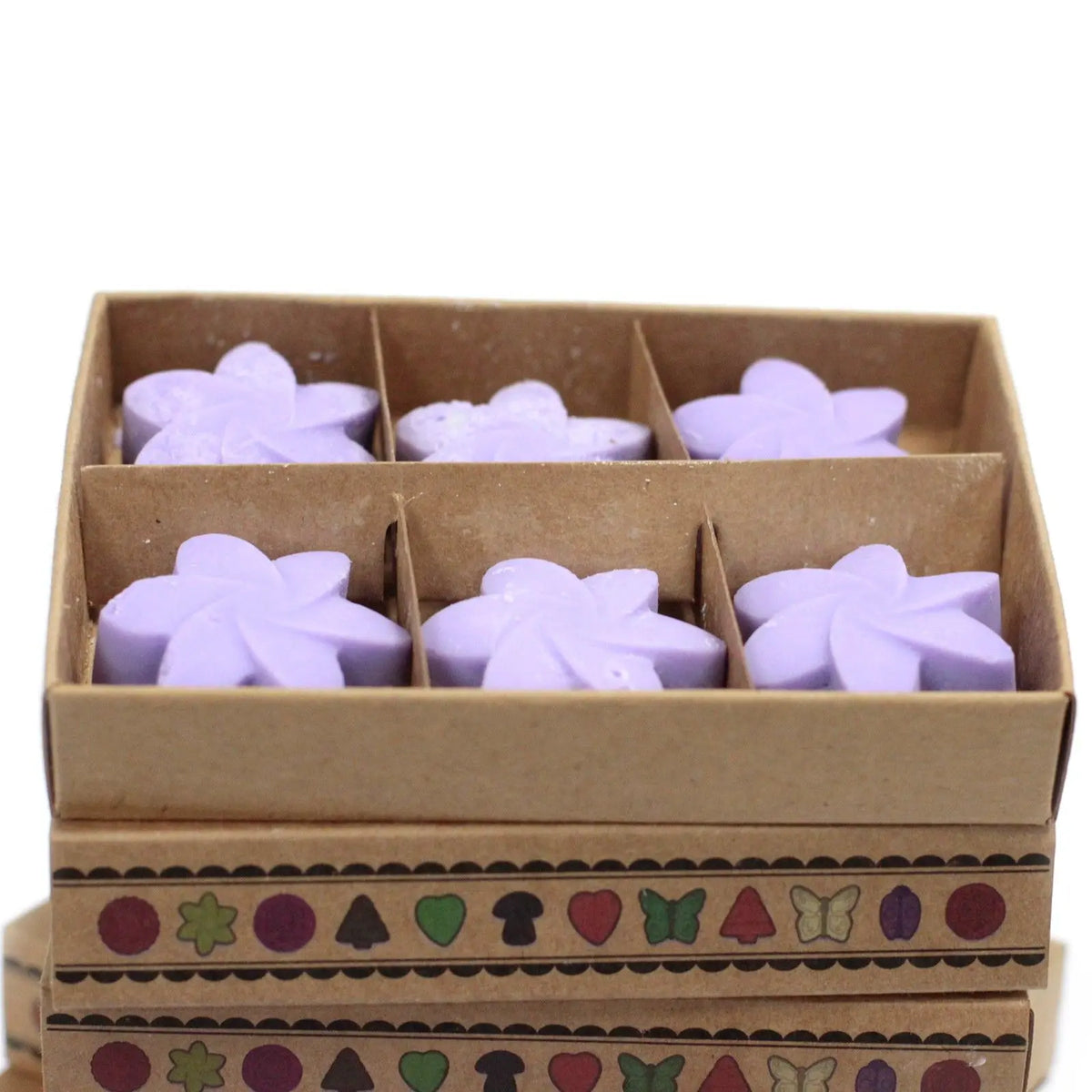 Seis ceras de soja lilas en forma de flor dentro de una caja de cartón decorada con motivos geométricos y naturales.