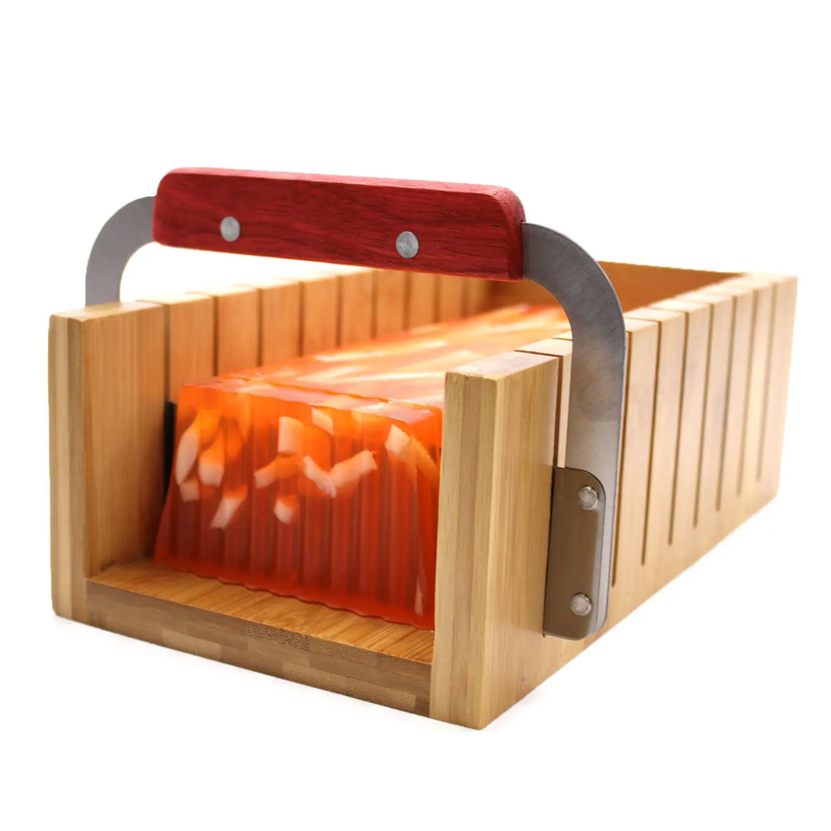 Cortador de madera para jabón con guía de corte y cuchilla metálica con mango rojo, sobre fondo blanco.