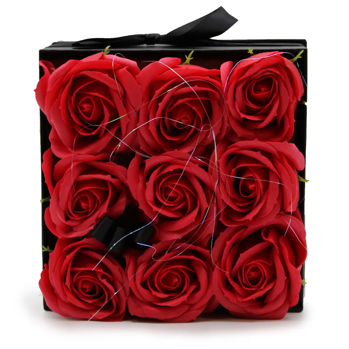Caja cuadrada negra con 9 rosas rojas de jabón dispuestas en cuadrícula, decorada con un lazo y finos hilos brillantes.