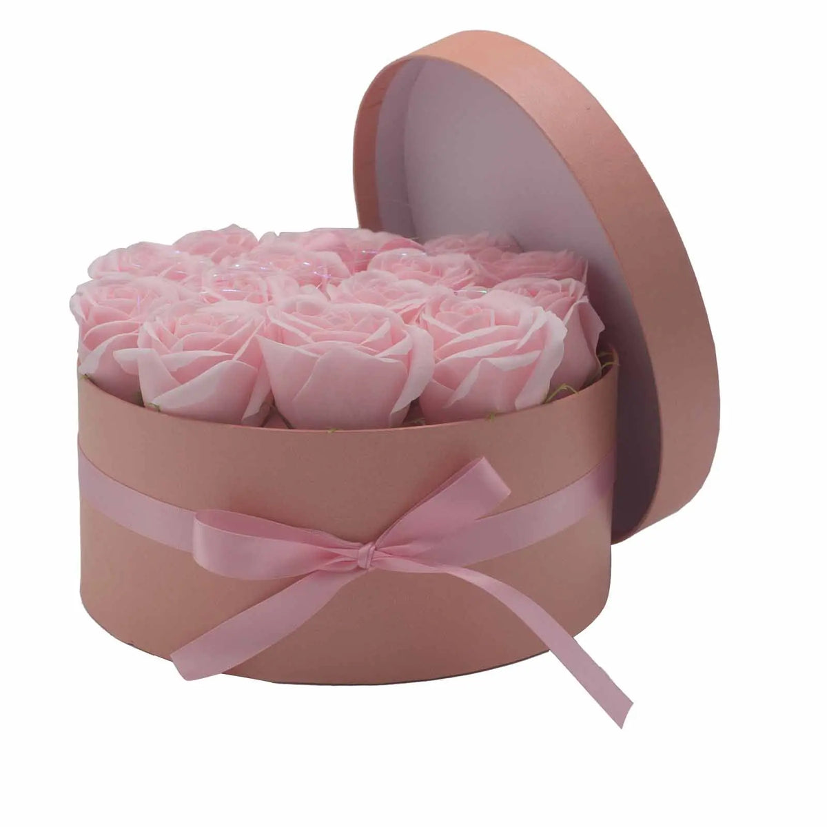 Caja redonda rosa con 14 flores de jabón rosa pastel, decorada con un lazo elegante y tapa abierta sobre fondo blanco