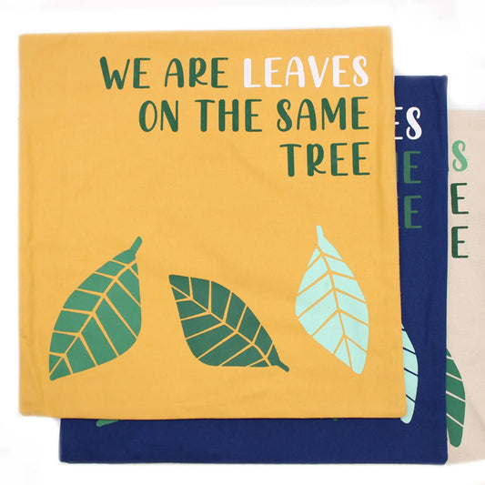Tres fundas de cojín de algodón con estampado de hojas y la frase "We are leaves on the same tree" en amarillo y azul.