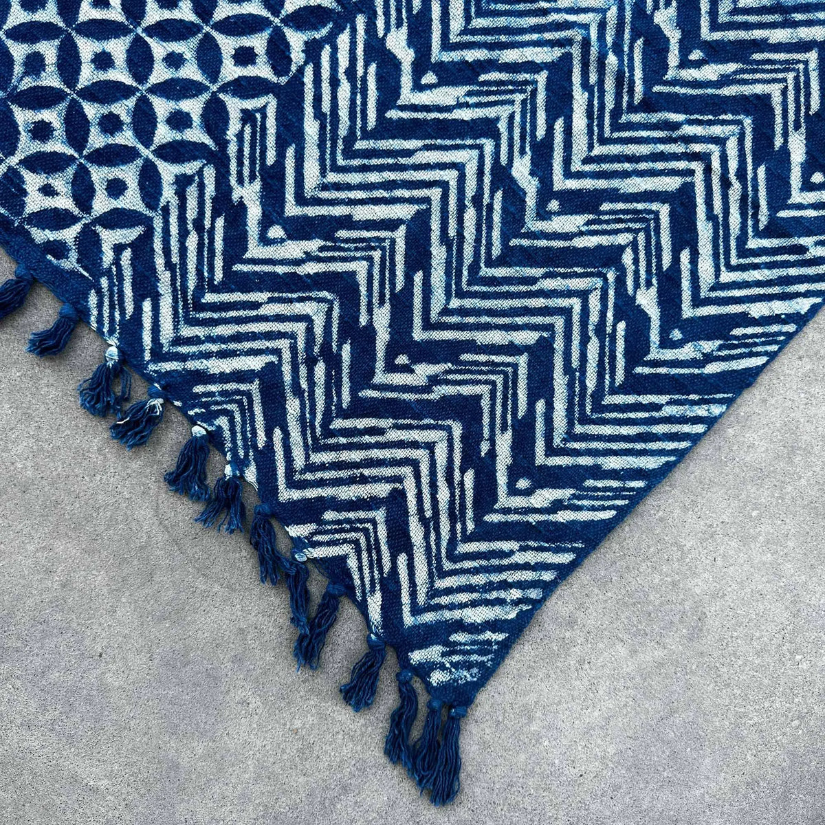 Alfombra azul marino con patrones geométricos en tonos claros y flecos, ideal para decoración moderna.