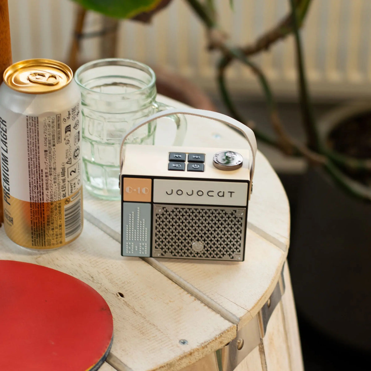 Altavoz Bluetooth Jojocut C10 estilo retro en beige y gris, diseño cuadrado con asa, sobre mesa de madera.