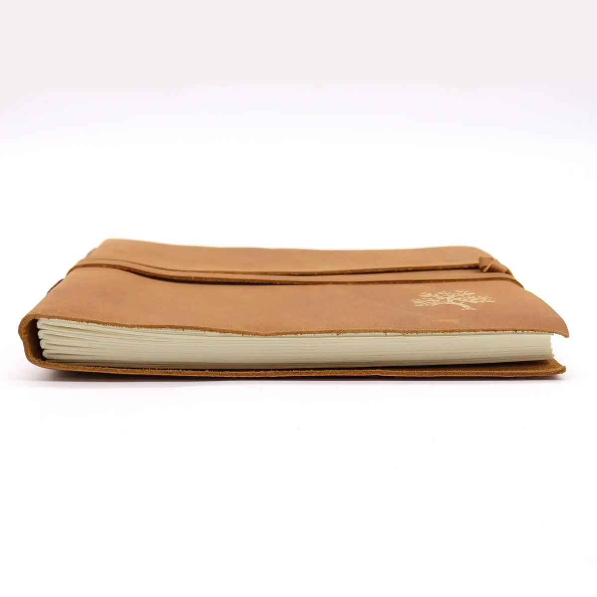 Cuaderno de viaje de cuero marrón con cierre elástico y grabado de árbol, visto de lado sobre fondo blanco.