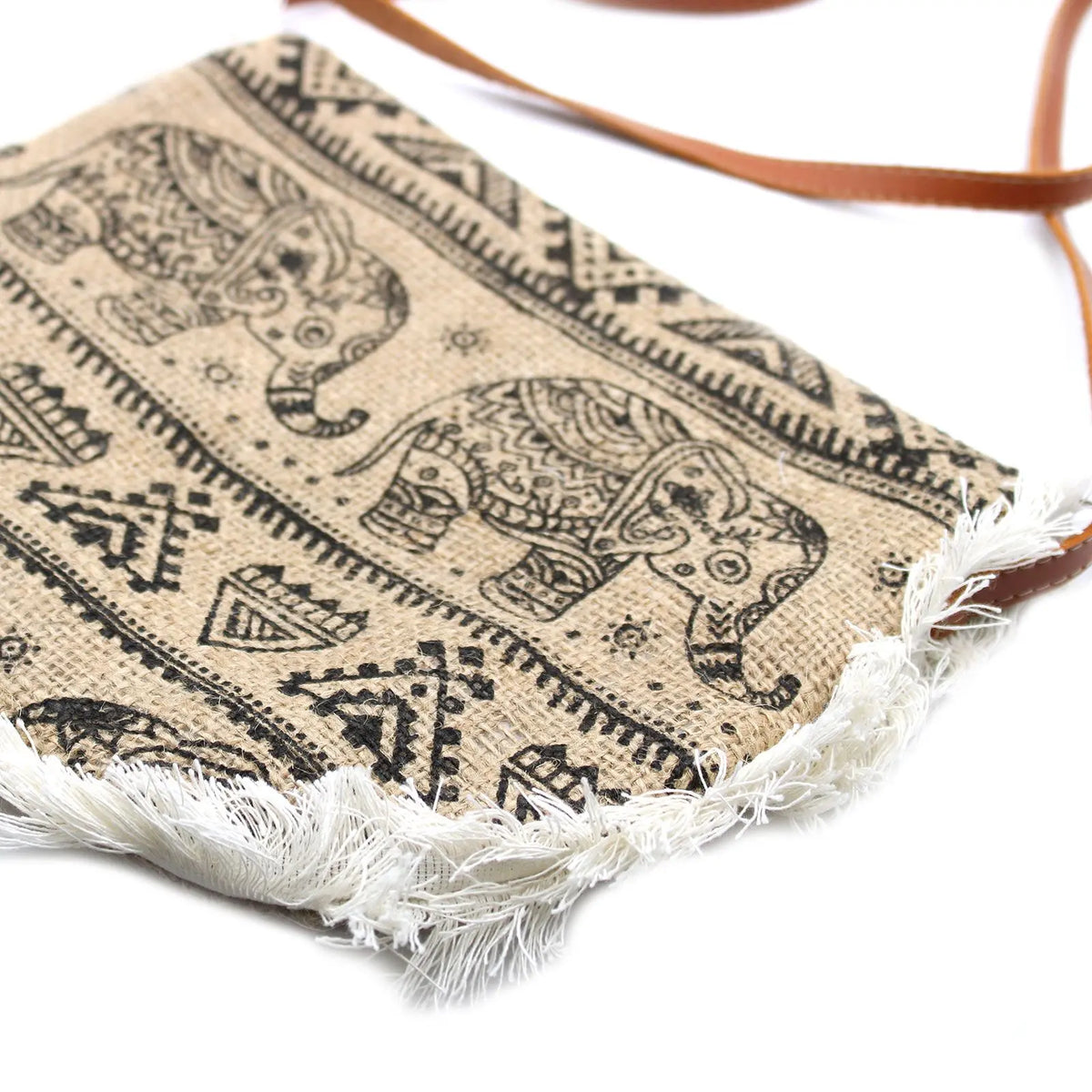 Bolso bandolera de yute color beige con estampado de elefantes en negro, flecos blancos inferiores y correa marrón.