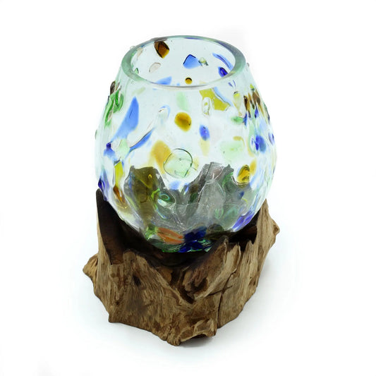 Cuenco de vidrio fundido con motas de colores sobre una base de madera natural con formas orgánicas.
