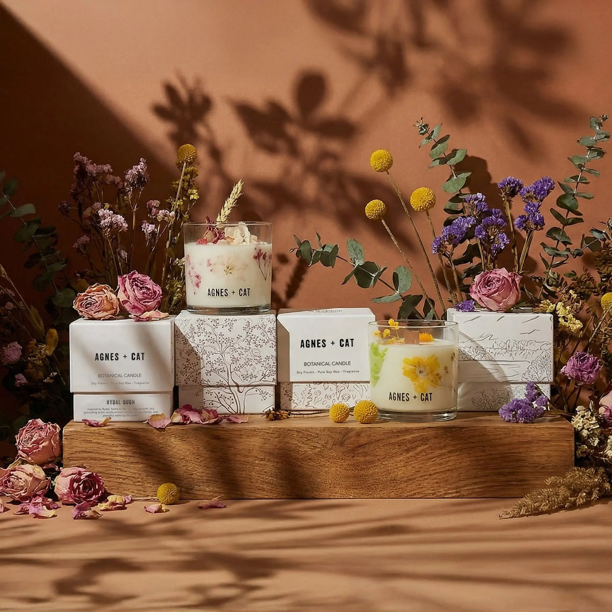 Velas aromáticas en frascos de vidrio, colores blanco y amarillo, con flores secas, estilo botánico y natural.