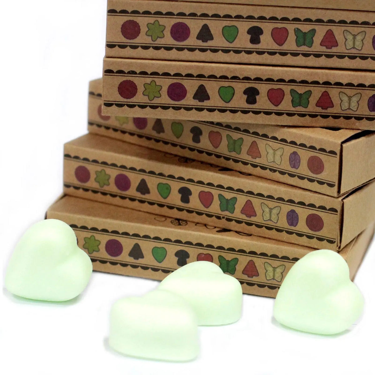Pila de cajas de cartón decoradas con iconos, junto a cuatro ceras de soja en forma de corazón de color verde claro.