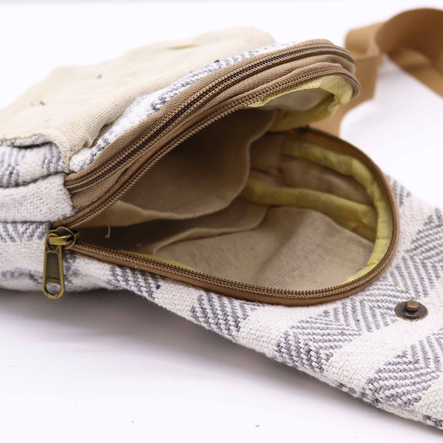 Bolso bandolera de algodón con tejido geométrico gris y blanco, cierre de cremallera y compartimentos interiores.