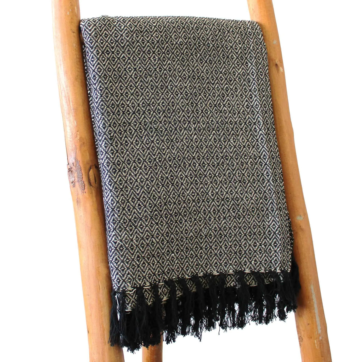 Manta de algodón negro y beige con diseño geométrico y flecos, perfecta para decoración moderna.