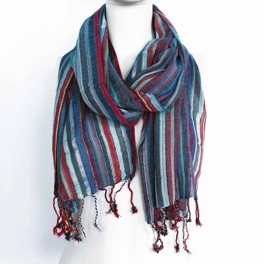 Bufanda bohemia con rayas verticales en tonos azul y rojo, de tela ligera y flecos en los extremos. Sobre maniquí.