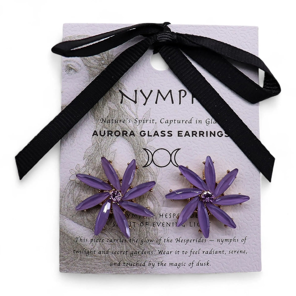 Pendientes en forma de flor color lavanda con pétalos de cristal y centro brillante sobre cartón decorado con lazo.