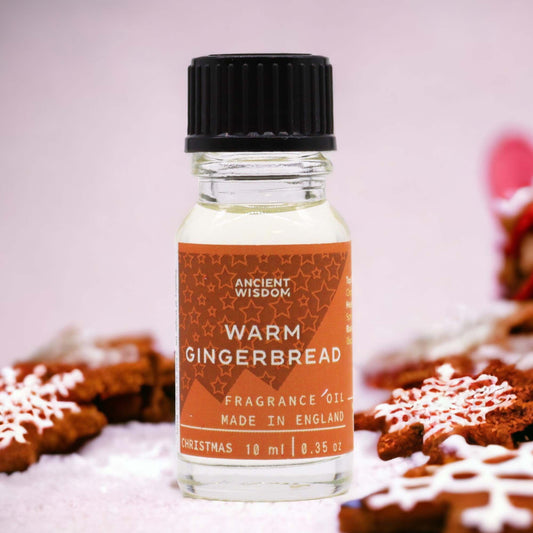 Frasco de vidrio de 10ml con tapa negra y etiqueta naranja de galleta de jengibre sobre galletas navideñas escarchadas.