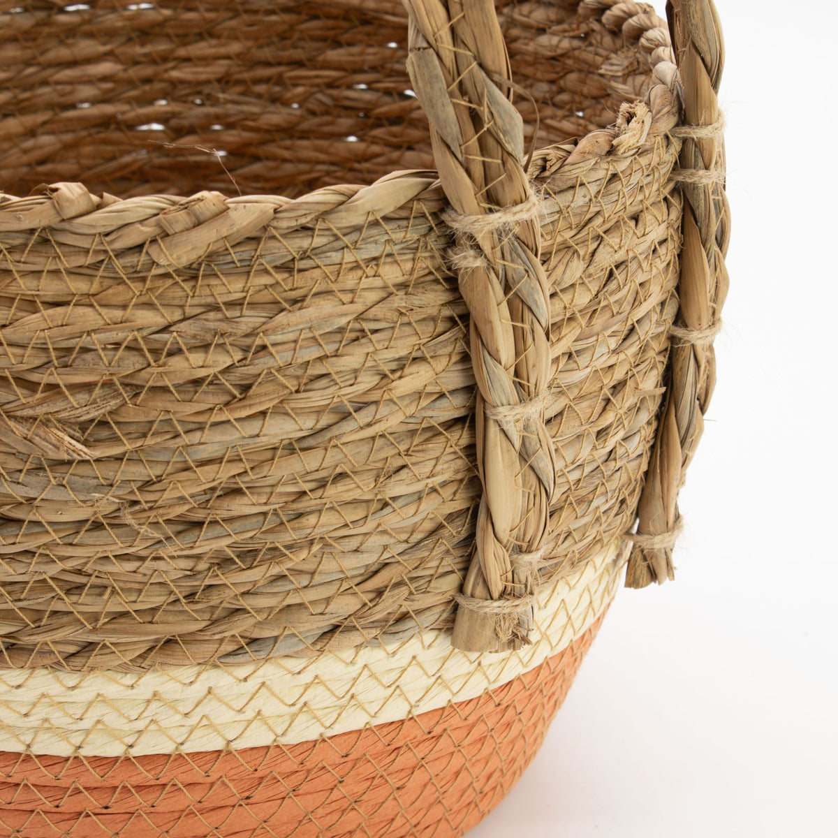 Cesta artesanal de pasto marino y hoja de plátano, con trenzado natural, base naranja y asa reforzada, estilo rústico.