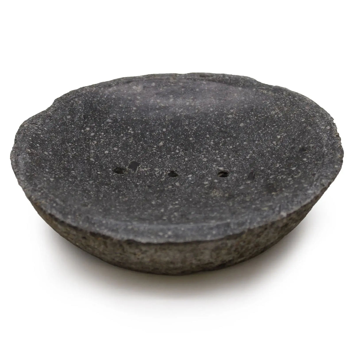 Jabonera Ancient Wisdom de piedra de río gris oscuro, forma circular cóncava con orificios de drenaje sobre fondo blanco.