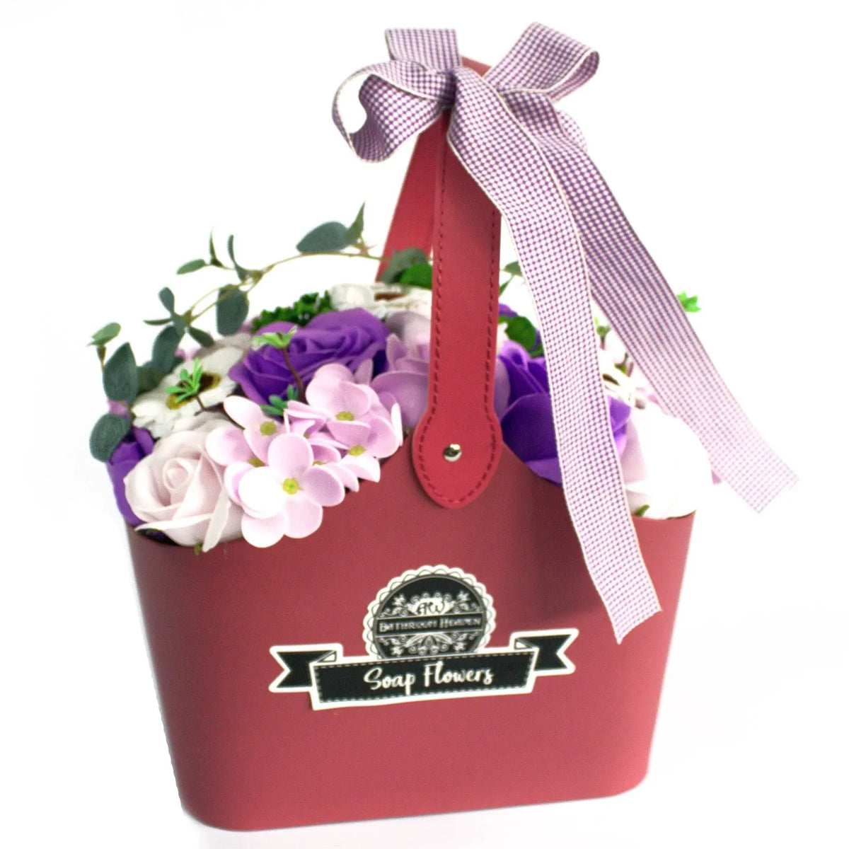 Cesta roja con flores de jabón en tonos morados y blancos, decorada con un lazo de cuadros lila y asa.