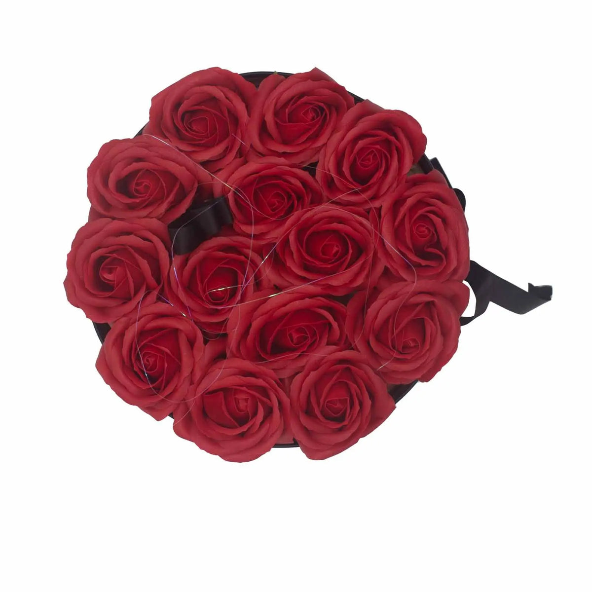 Caja redonda negra con 14 rosas rojas de jabón dispuestas artísticamente, vista desde arriba.